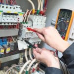 Elektriker prüft mit einem Multimeter die Spannung an Komponenten in einem Schaltschrank