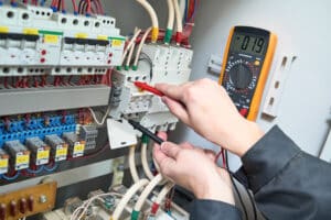 Elektriker prüft mit einem Multimeter die Spannung an Komponenten in einem Schaltschrank